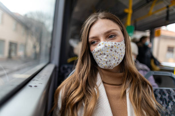 istock Woman with protective face mask looking through the window while traveling by bus 1300036520
