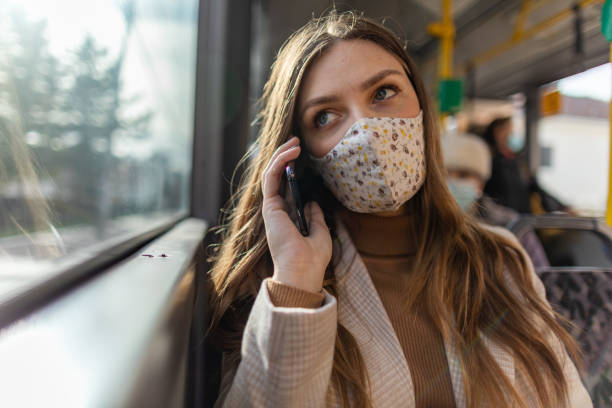 istock Young woman with protective face mask using phone while traveling by bus 1300036522
