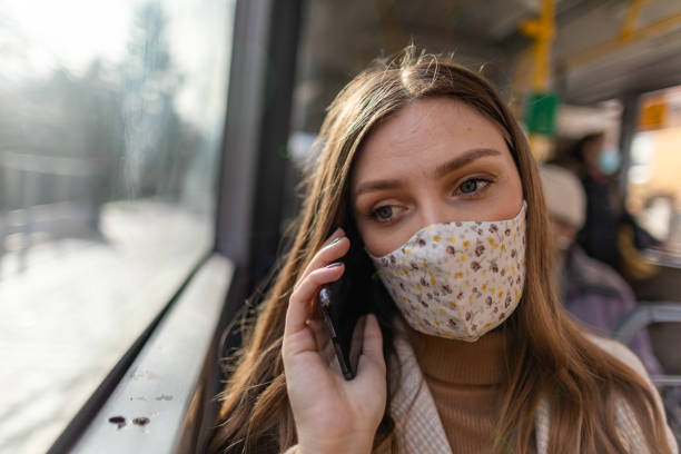 istock Depressed woman with protective face mask using phone and looking through the window while traveling by bus 1300036596