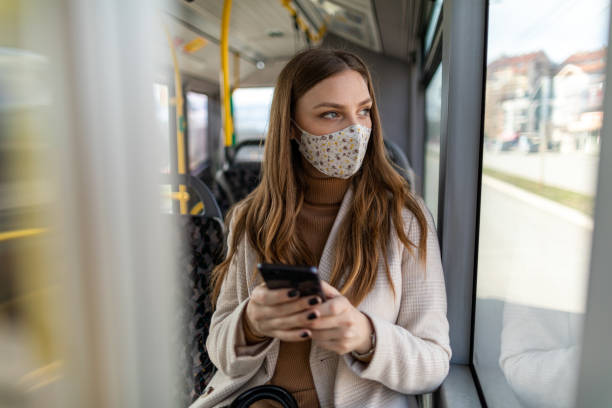 istock Young woman using phone while traveling by public transportation during coronavirus pandemic 1300036668