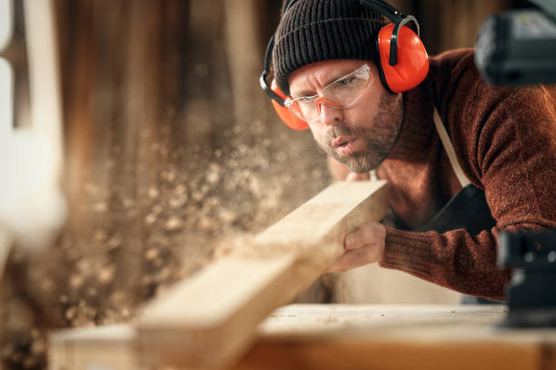 carpenter blowing sawdust from wooden plank - carpenter carpentry craft skill imagens e fotografias de stock