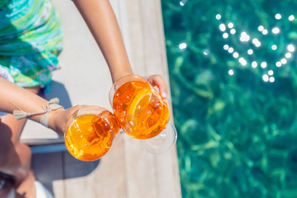 Women  toasting with a spritz cocktail on a deck over the ocean. Turquoise ocean is crystal clear. High angle view with copy space. Focus on background