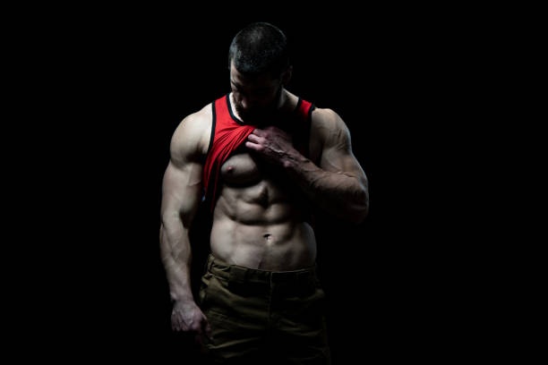 istock Man Standing and Flexing Muscles on Black Background 1300047726