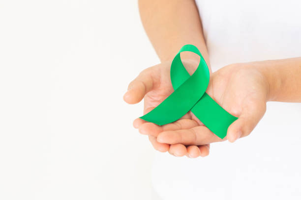 istock Hand holding Emerald green or jade green ribbon curl on white background with copy space, symbol for Liver Cancer awareness, World Cancer Day. Healthcare or hospital and insurance concept. 1300047809