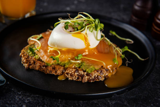 黒い背景にサーモンとポーチドエッグと健康的なトーストのクローズアップ - sandwich breakfast boiled egg close up ストックフォトと画像