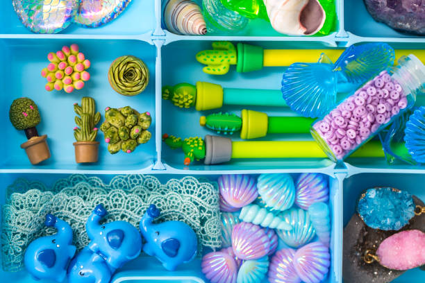 istock Container with cute toy items such as shells, pens, plastic succulents, crystals and stones, cartoon elephants, lace. Items arranged by color, top view 1300059661
