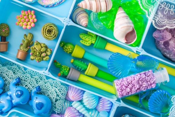 istock Container with cute toy items such as shells, pens, plastic succulents, crystals and stones, cartoon elephants, lace. Items arranged by color, top view 1300059700