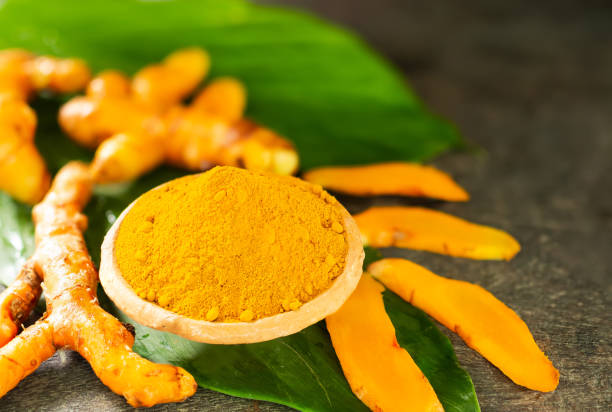 istock Turmeric powder on cup with slice raw turmeric on wood background. Thai herbs concept. 1300060775