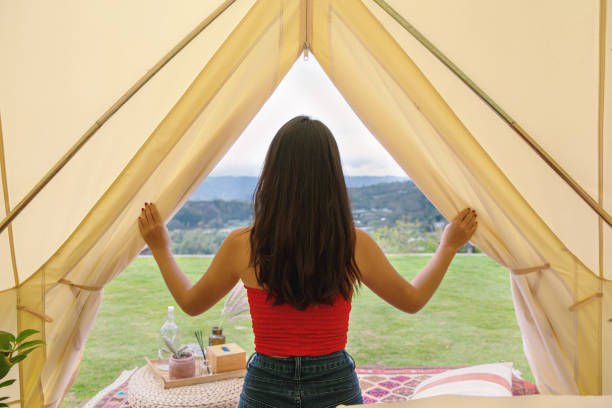 Waking up To a Beautiful Scenic View Rear view shot of an unrecognizable Asian woman opening the door flaps of a luxurious tent. She's waking up in the morning with a scenic view in front of her tent. glamping photos stock pictures, royalty-free photos & images