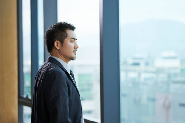 asian corporate executive standing by the window looking out