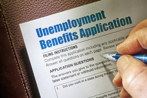 Unemployment Benefits Application with hand and pen