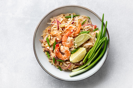 Pad Thai, Thai Fried Noodles with shrimp and vegetables on a light gray background, top view