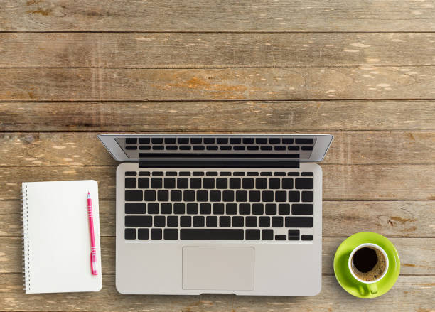 istock Laptop computer with notebook and cup of coffee on wooden desktop in office workplace 1300071629