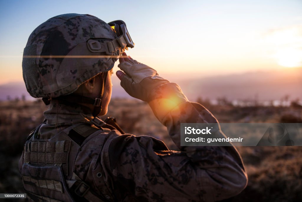 Female Army Solider Saluting against sunset sky Military Stock Photo