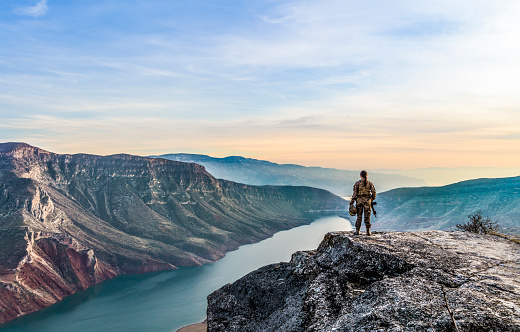 Female Soldier Standing on top of Cliff at sunset