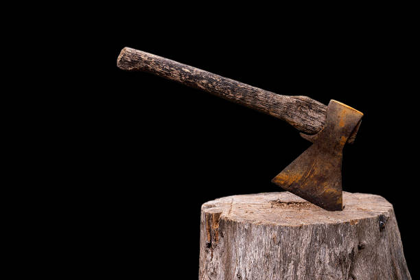 Old Axe stuck in a tree on a black background The front view is isolate. The metal is old. axe stock pictures, royalty-free photos & images