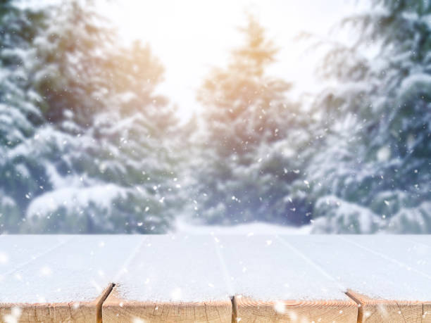 istock Wooden table with snow over blurred abstract winter landscape background 1300076717