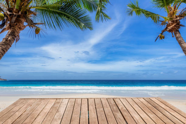 istock Beach wooden table and coconut palms with party on tropical beach background. 1300077621