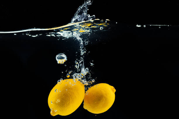 istock Lemons diving into the water with a splash against black background 1300077852