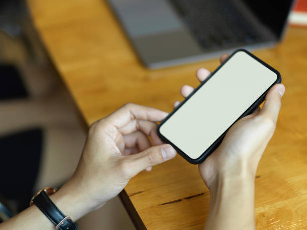 istock Male hand holding smartphone include clipping path on wooden table 1300078814