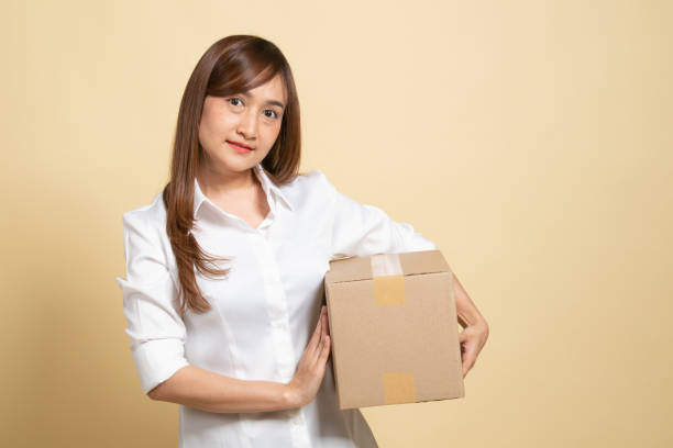 delivery, relocation and unpacking.  young asian woman holding cardboard box. - ped imagens e fotografias de stock