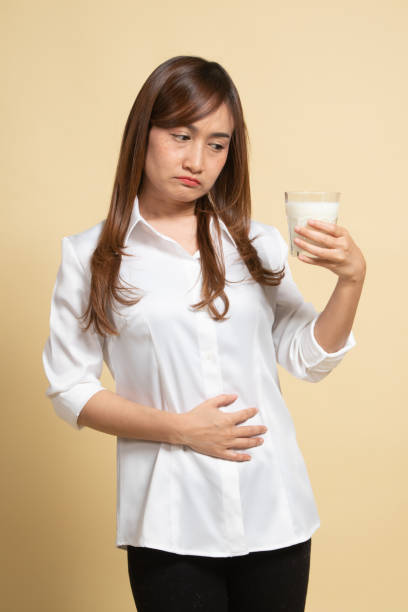 la femme asiatique buvant un verre de lait a obtenu le mal d’estomac. - got milk photos et images de collection