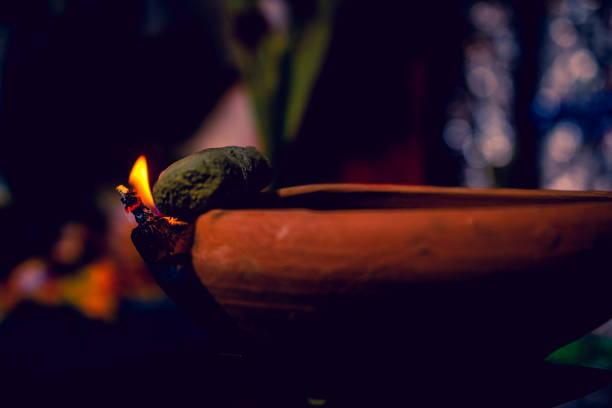 fotografia criativa de uma lâmpada de óleo de lama em chamas realista em diwali, um festival indiano à noite. chama de fogo vermelho, amarelo, laranja colorido aceso no fundo escuro da sombra noturna com efeito de grão de ruído. - gold bright brightly lit light - fotografias e filmes do acervo