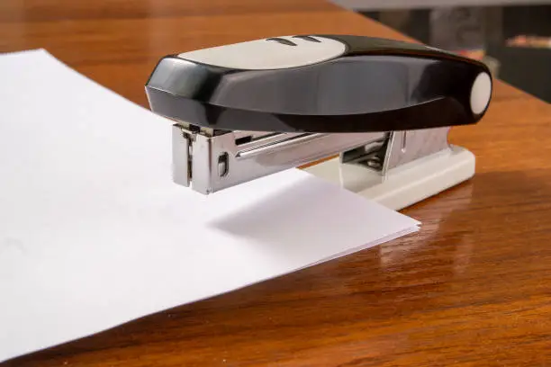 Photo of a stack of paper is stapled together with a stapler