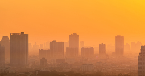 Air pollution. Smog and fine dust of pm2.5 covered city in the morning with orange sunrise sky. Cityscape with polluted air. Dirty environment. Urban toxic dust. Unhealthy air. Urban unhealthy living.