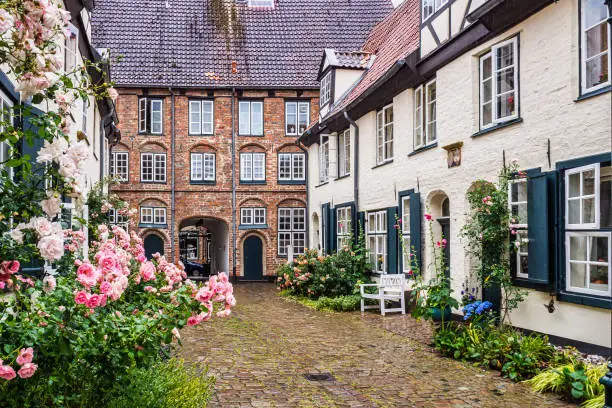 Beautiful cozy courtyard with old houses and flowers in the street of old the town Lubeck, Germany