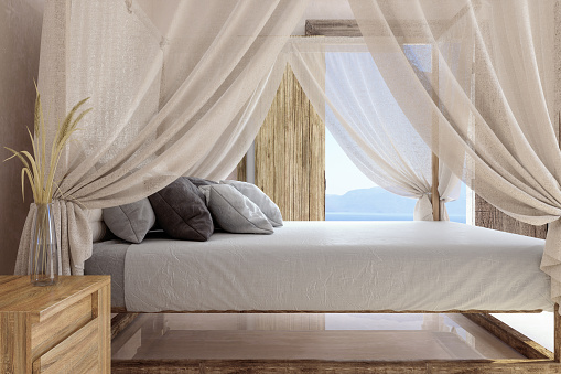 Side View Of Hotel Bed With Mosquito Netting And Seascape Background.