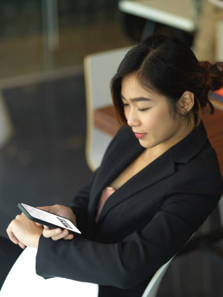 istock Businesswoman looking on wristwatch while using smartphone in office room 1300094180