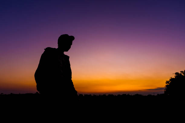 istock silhouette dark young man wearing a hat standing emotions with evening Twilight sky with cloud in the winter season at sunset Abstract background.Copy space for your 1300095583