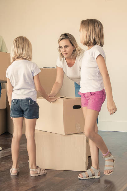 istock Happy new home owners with two kids holding cardboard b 1300097710