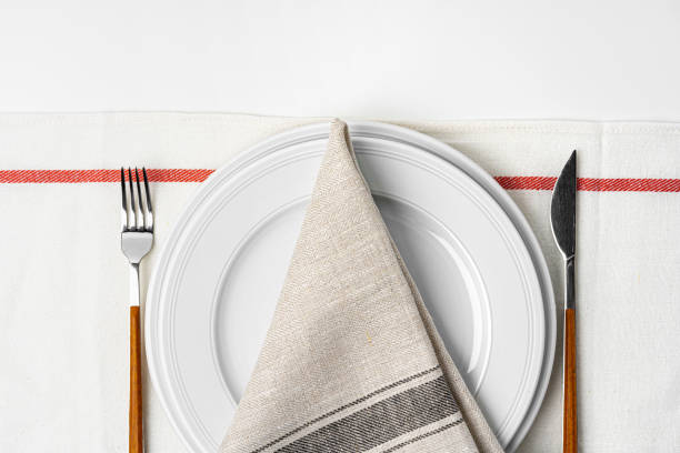 istock Fork, knife and plate on towel. Isolated on white background. 1300098015