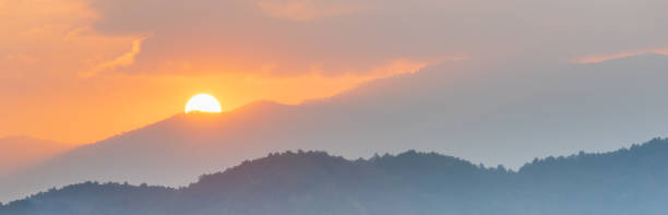 istock Colorful sunset at mountain ridge with flower field foreground. 1300098402