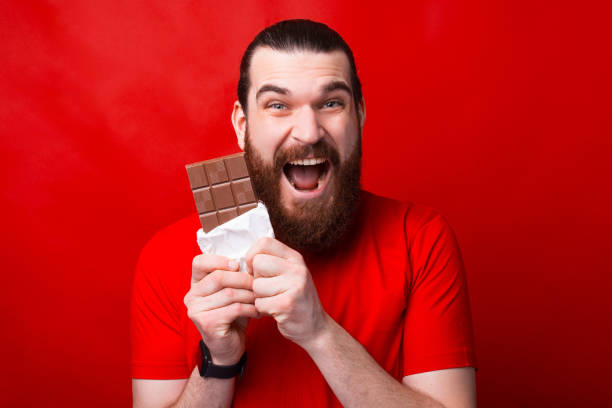 istock A very excited man is eating a chocolate in front of camera looking at it 1300099176