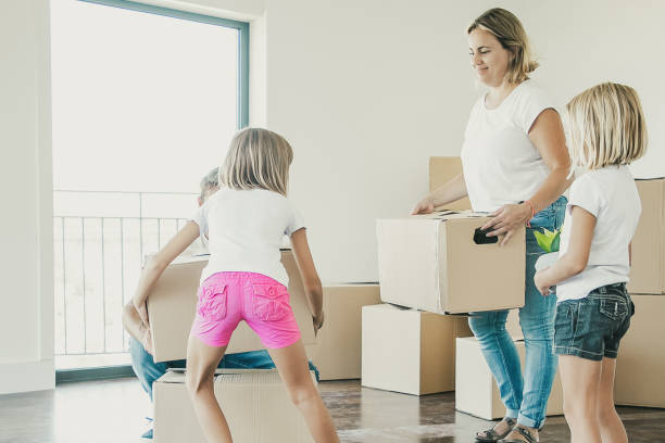 istock Happy family with two kids holding cardboard boxes 1300100437