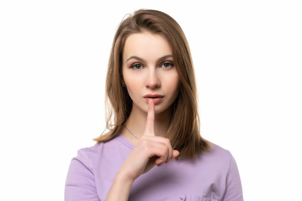 istock close up young pretty woman is pressing finger to lips, making silent gesture asking to keep secret, says shush or hush 1300102156