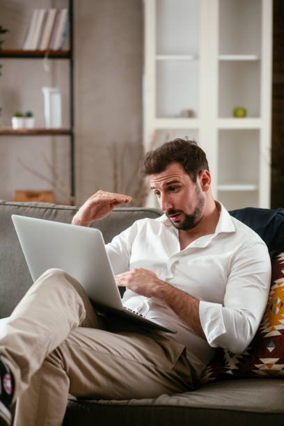istock Businessman sitting on sofa having video call 1300102500