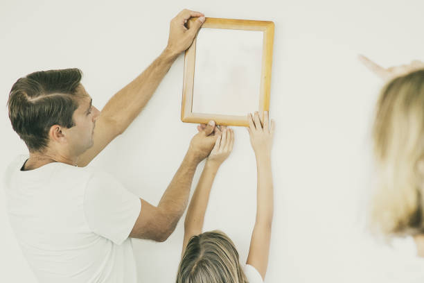 istock Father and daughter hanging up frame with copy space 1300102599