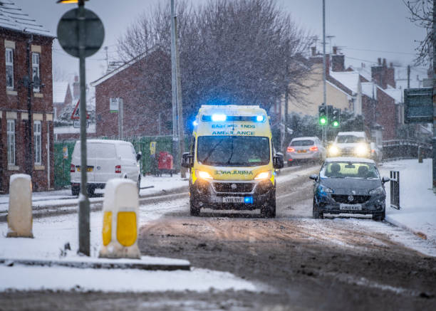 nhs emas ambulance service sur 999 intervention d’urgence avec de la neige sur les feux bleus de la route pendant les chutes de neige - pedestrian accident england street photos et images de collection