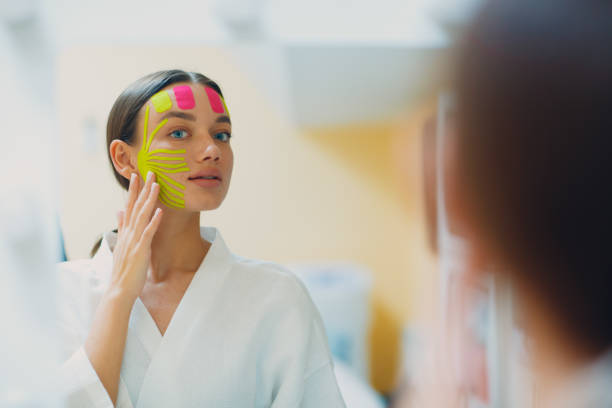 Beautiful woman applying tape lifting treatment on face Beautiful woman applying tape lifting treatment procedure on face corrective action stock pictures, royalty-free photos & images