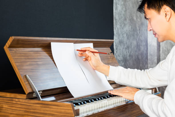 asian male songwriter writing a hit song while playing piano. songwriting concept asian male songwriter writing a hit song while playing piano. songwriting concept chord stock pictures, royalty-free photos & images