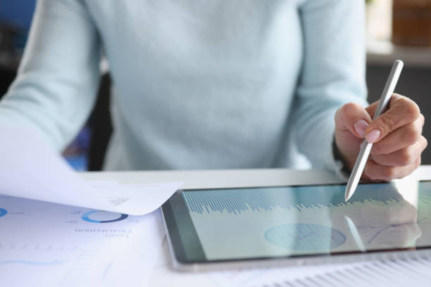 istock Woman holding documents in hands and working with tablet closeup 1300104810