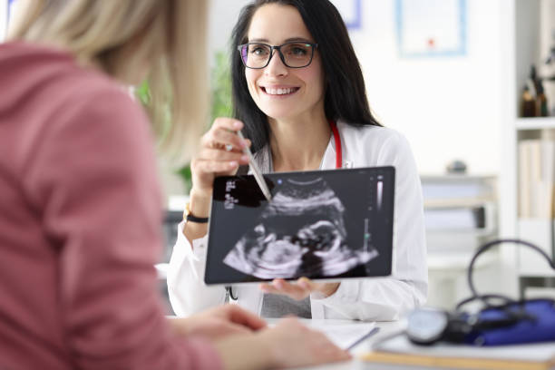 Gynecologist showing patient ultrasound of fetus on tablet Gynecologist showing patient ultrasound of fetus on tablet. Diagnosis and management of pregnancy concept in vitro fertilization photos stock pictures, royalty-free photos & images