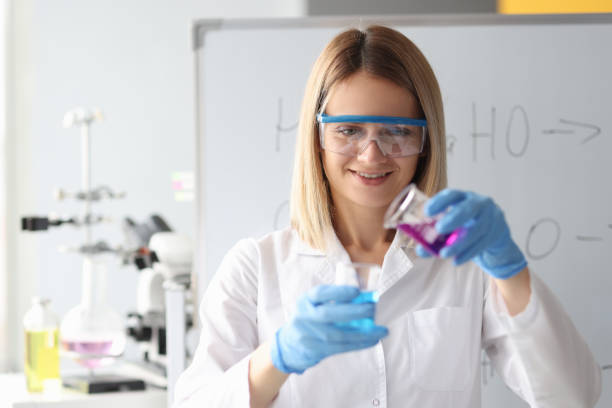 istock Woman chemist in protective glasses pouring liquid from flask 1300104850