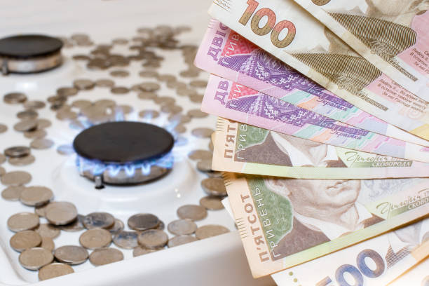 Ukrainian hryvnias against the background of coins and gas burners on the stove. Gas and utilities price. Utility prices ukrainian currency stock pictures, royalty-free photos & images