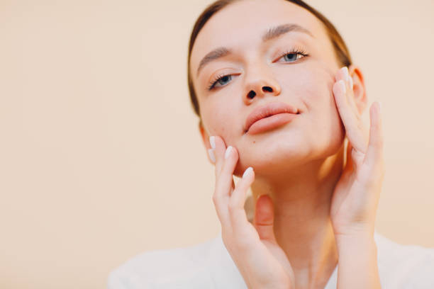 istock Young woman applying cosmetic white cream on her face 1300104970