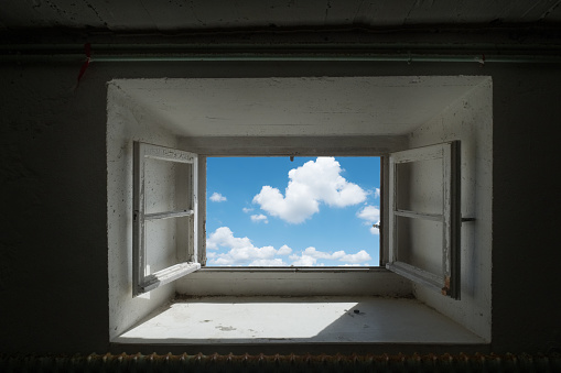 A window open to a beautiful blue sky with clouds